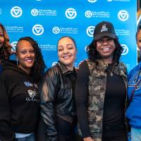Group of five event attendees posing for photo in front of GV back drop